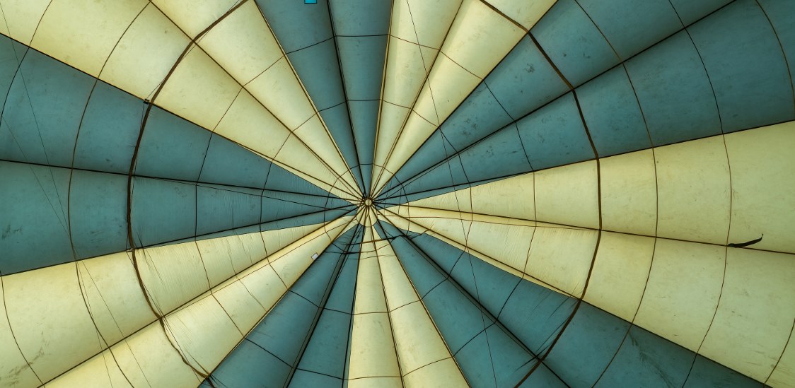 Looking up inside a green and yellow hot air balloon.