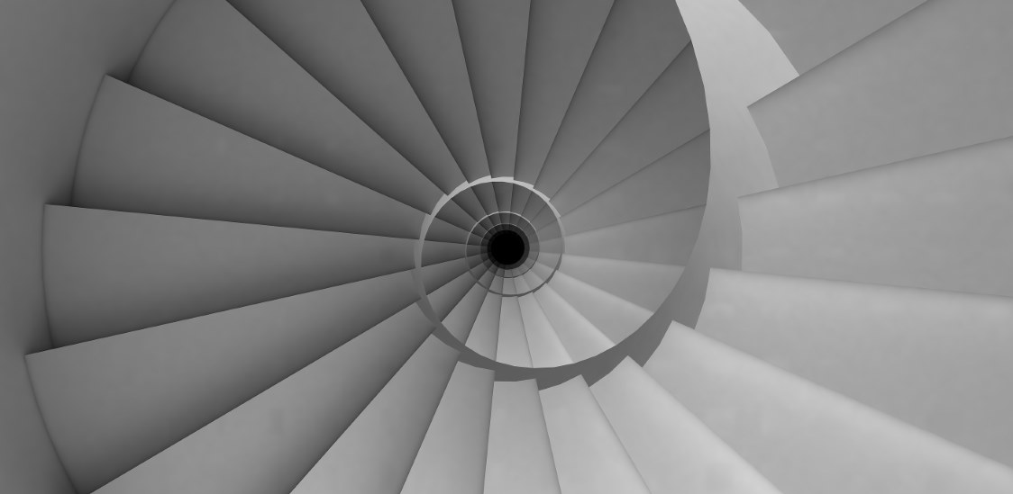 View from above of a spiraling, monochrome staircase.