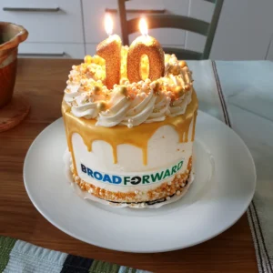 A celebratory cake with golden icing and a "10" candle, marking BroadForward's 10th anniversary.