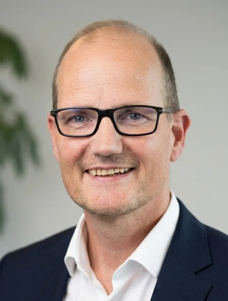 Portrait of a smiling man in glasses wearing a suit.