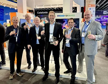 A group of people celebrating with drinks at the BroadForward booth at the MWC, holding an award.